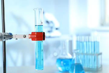Graduated cylinder with light blue liquid in laboratory. Space for text