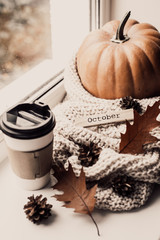 Cup of coffee, pumpkin, dried autumn leaves on window. Autumn composition.