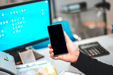 Young business woman in office at table and using smartphone