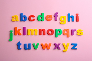 Plastic magnetic letters on pink background, flat lay. Alphabetical order