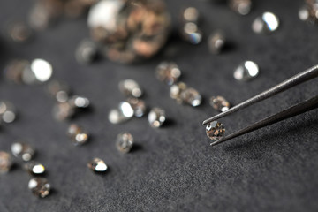 Tweezers with beautiful gemstone over grey table