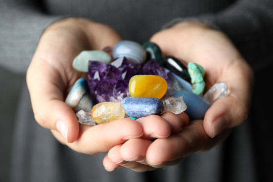 Woman holding pile of different gemstones, closeup