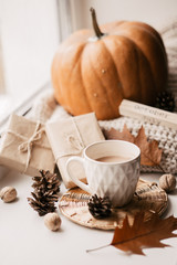 Cup of coffee, pumpkin, dried autumn leaves on window. Autumn composition.