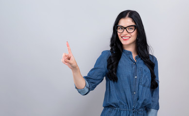 Young woman pointing at something on a gray background