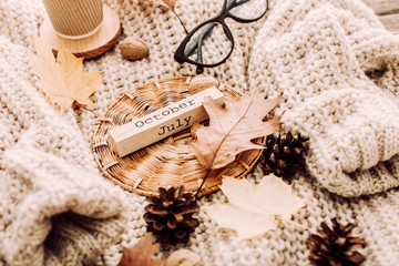 Cup of coffee, nuts, glasses, dried autumn leaves on sweater background. Autumn composition.