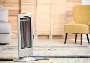 Modern electric infrared heater on floor at home. Space for text