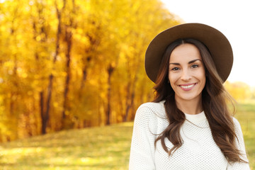 Beautiful happy woman wearing hat in park. Autumn walk