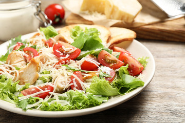 Delicious fresh Caesar salad on wooden table, closeup