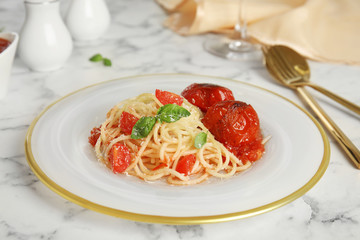 Tasty pasta with tomatoes, cheese and basil on white marble table
