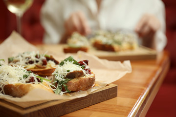 Delicious bruschettas with beef and cheese on wooden table, closeup