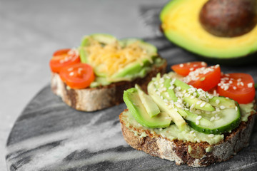 Delicious avocado sandwiches on marble board, closeup