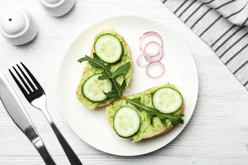 Flat lay composition with avocado sandwiches on white wooden table