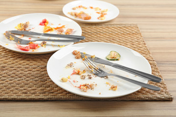 Dirty plates with leftovers on wooden table after party