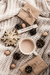 Fototapeta na wymiar Winter composition. Coffee cup, candle, nuts and on sweater background.