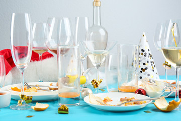Dirty tableware with leftovers on light blue cloth after party