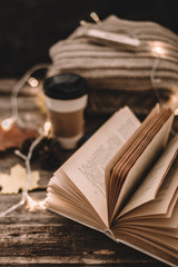 Autumn composition. Cup with coffee, garland, book, cones on a wooden background.