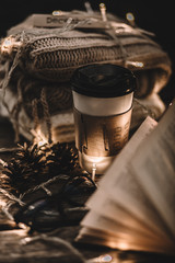 Autumn composition. Cup with coffee, garland, book, cones on a wooden background.