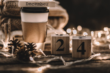 Winter composition. Cup with coffee, garland, book, cones on a wooden background.