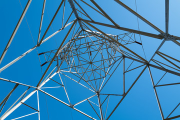 Obraz premium Looking upward through a high voltage tower at a clear blue sky