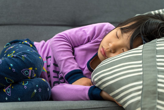 Little Asian child girl sleeping on couch with purple color pajamas