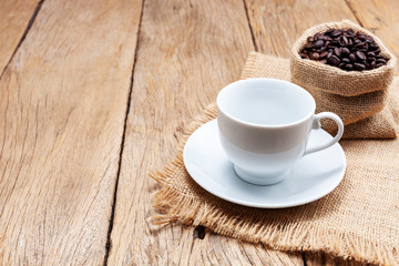 Empty white coffee cup with coffee beans on wooden plank floor background
