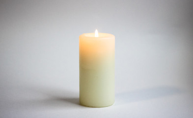 Fototapeta na wymiar a white candle stands on a gray background, a fire burns