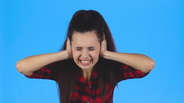 Young female is closing her ears and shouting. Slow motion