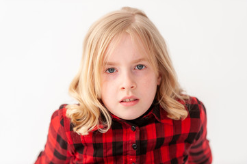 Headshot of a pretty blonde preteen girl with neutral expression on a white studio background