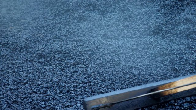 Worker operating asphalt rake during road construction and repairing works