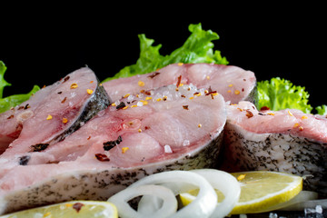 fish steaks with lettuce spices and tomatoes on a black background