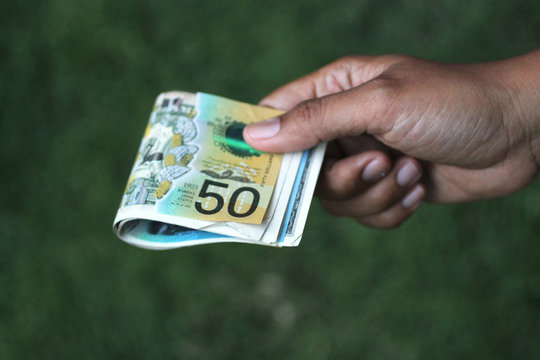 Paper Money In Hand. Young Woman Or Man Holding 50 AUD Australian Dollar On Green Background. Pay Day Concept. Copy Space For Text Or Design.