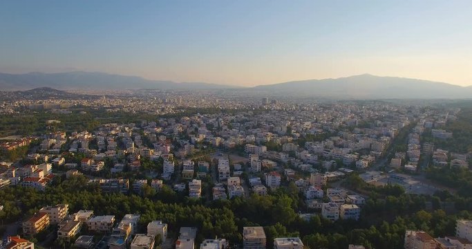 Athens Greece at sunrise with massive city and the acropolis in the distance at sunrise. Realtime aerial drone shot of a huge sprawl of houses apartments and buildings.