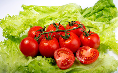 cherry tomatoes on lettuce leaves on white background
