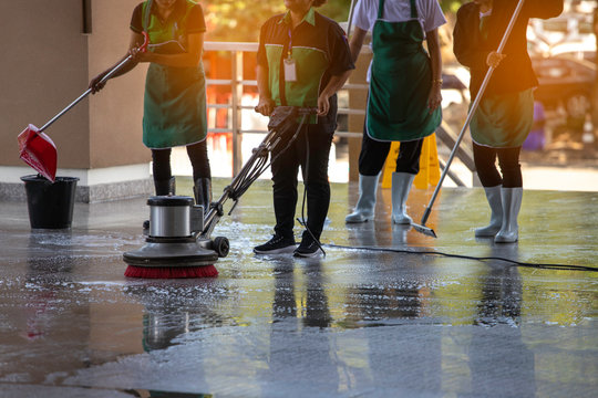 The workers cleaning floor exterior walkway using polishing machine and chemical or acid