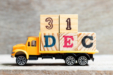 Truck hold letter block in word 31dec on wood background (Concept for date 31 month December)