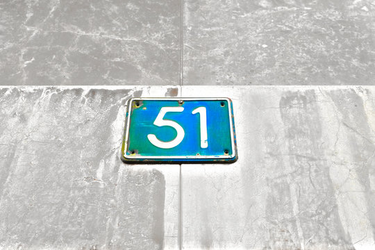 Number 51, fifty-one, blue plate on gray surface.
