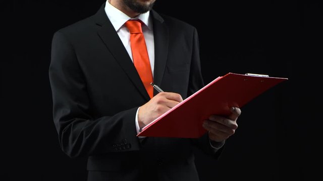 Businessman fills papers in red folder with pen, then looks through them. Concept of planning, business. Mockup ready for your text or product.