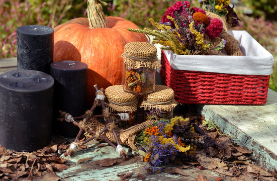 Black candles, pumpkin and pentagram with dry autumn flowers on planks