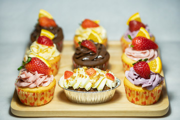 Colorful cakes in a wooden tray Decorated with strawberries and oranges