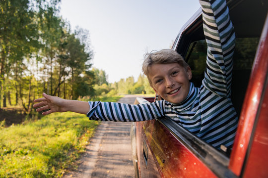 Happy Kid Travel By The Car. He Popped Out Of The Window