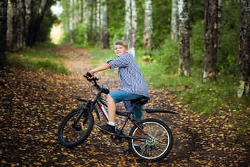 Happy boy on a bicycle in park studies to ride sharply braked on a dirt.