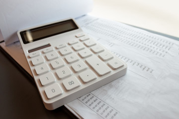 White calculators and financial documents on wooden office desk