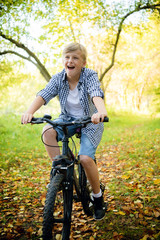 Boy in countryside riding bike in summer park smiling at camera