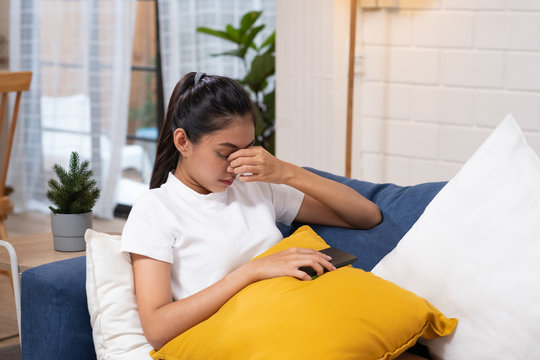 Young asian woman feeling  stress  and closed eyes ,she is  suffering from headachelying down on sofa in living room,tired  female office worker massaging eyes,