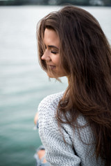 Beautiful dreaming woman sitting by the lake.