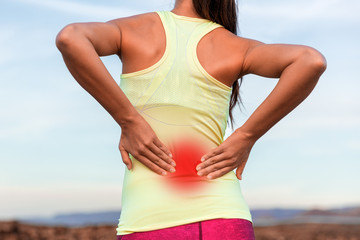 Back pain sport injury woman with inflammed area in red halo. Young athlete touching massaging...