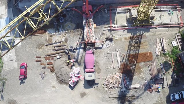 Building construction during workers concreting slab on last floor on a sunny day. Aerial view.Tilt up.