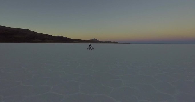 View of a Man Riding a Bicycle at Sunrise in the World's Largest Salt Desert, Natural Wonder of the World.