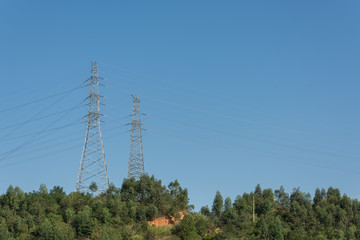 Obraz premium Towering 2 high-voltage towers in the woods on the top of the mountain