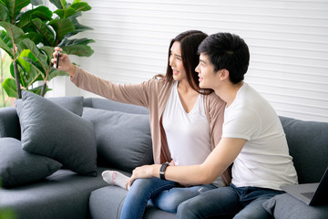 Asian couple smiling taking a selfie photo with smartphone